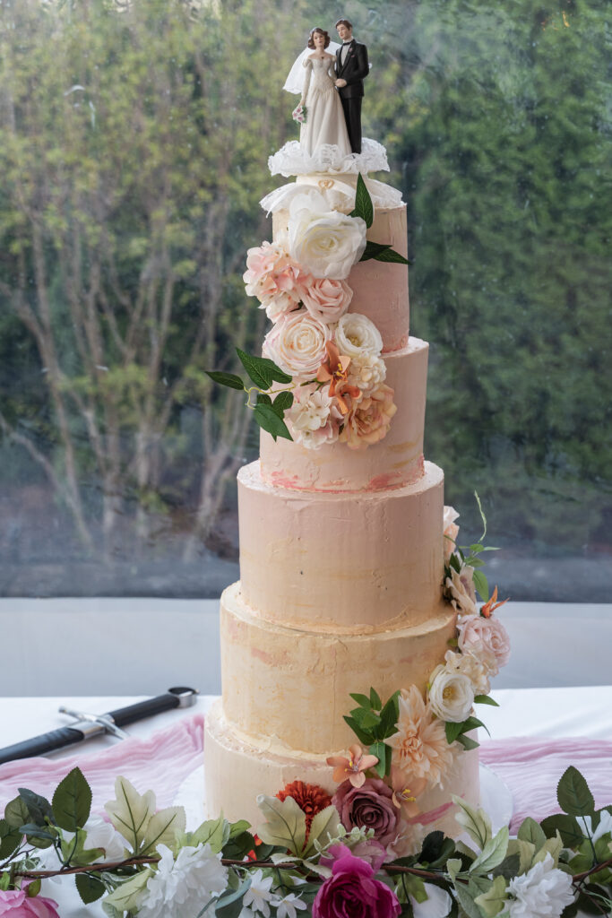 Custom 5-Tier Sunset Wedding Cake in Harford County handmade with beautiful florals and traditional bride and groom wedding topper